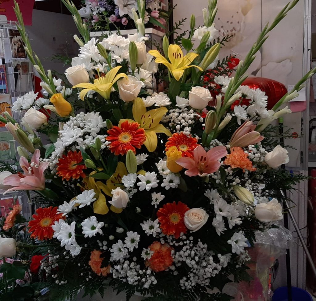 Centro funerario esta compuesto por una base ceramica de 30 cm donde se colocan las distintas flores cortadas , se compone de una gran variedad de flor como son liliun amarillos gladiolos blancos, gerberas naranjas , margarita blanca, rosas blancas.

