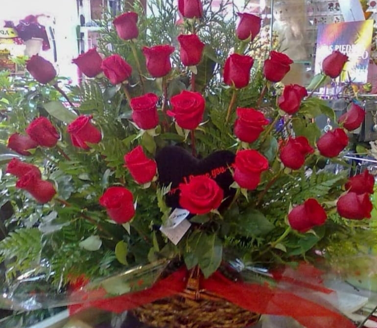 Centro floral para difuntos compuesto de hoja de helecho hojas verdes de thuja y 24 rosas rojas
