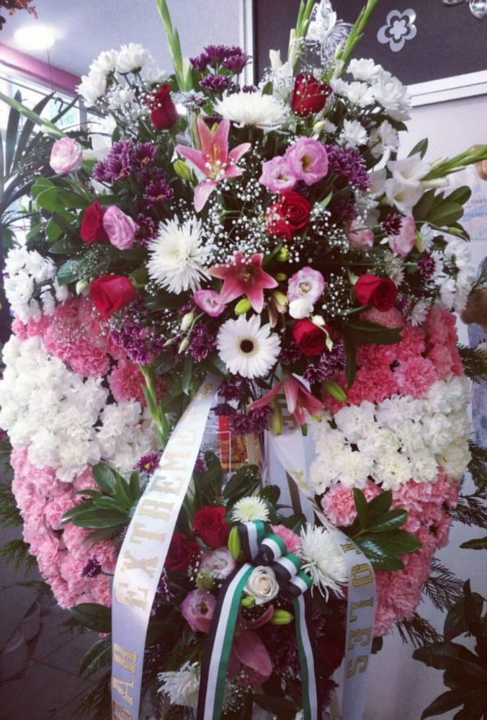 corona funeraria de flores con claveles blancos y rosas cinta de condolencia, gladiolos , rosas rojas , anastasias moradas